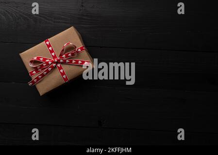 Einzelne Geschenkbox auf schwarzem Holz. Geschenk für valentinstag. Stockfoto