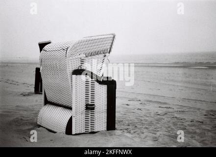 Eine Graustufenaufnahme eines mit Kapuze versehenen Strandstuhls. Stockfoto