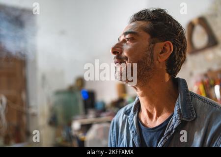 Vierzig Handwerker, die während einer Pause in seinem Arbeitsraum eine Zigarette rauchen - People Lifestyle-Konzept Stockfoto