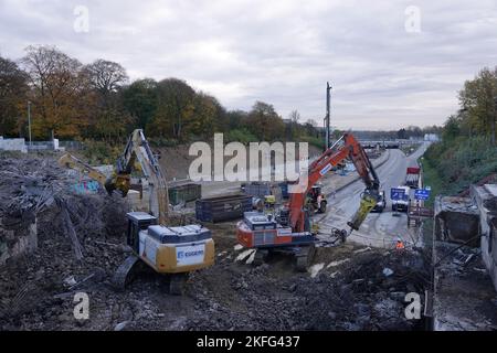 Hamburg, Deutschland. 18.. November 2022. Bagger reißen eine Brücke über die A7 in Hamburg ab. Die Autobahn nördlich und südlich des Elbtunnels wird von sechs auf acht Fahrspuren erweitert. Im Altona-Gebiet wird er mit einer gut zwei Kilometer langen Lärmschutzabdeckung versehen. Dafür sollen jetzt drei Brücken abgerissen werden. Quelle: Kilian Genius/dpa/Alamy Live News Stockfoto