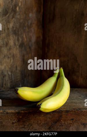 Bananen ruhen auf einer rustikalen Holzoberfläche in sanfter Beleuchtung Stockfoto