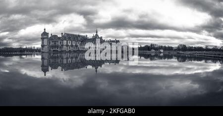 Domaine de Chantilly, Schloss Chantilly bei Sonnenuntergang, Spiegelung des Wolkenhimmels im Teich. Berühmtes Touristenziel in der Nähe von Paris. Stockfoto