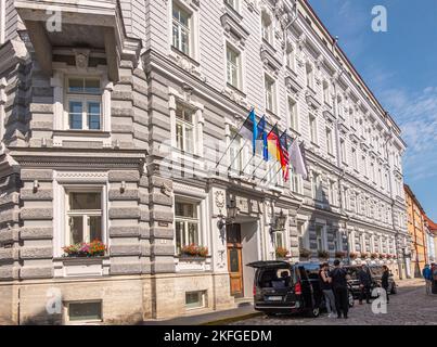 Estland, Tallinn - 21. Juli 2022: Flaggen über dem Eingang des Hotel Telegraaf hellgraues Steingebäude im klassischen Stil in der Venes Street. Schwarze Autos mit Peop Stockfoto