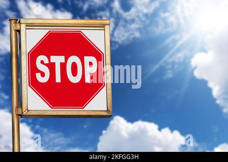 Nahaufnahme eines Stoppschildes vor einem klaren blauen Himmel mit Wolken und Sonnenstrahlen, Fotografie. Stockfoto