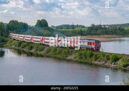 HELYULYA, RUSSLAND - 11. JUNI 2022: Doppeldeckerzug 'Moskau-Ruskeala' fährt in den Damm des Karmalanyarvi-Sees ein. Karelien Stockfoto