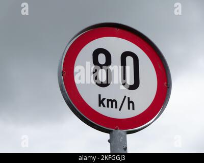 Ein Straßenschild, das die Geschwindigkeit von 80 km pro Stunde gegen den Himmel begrenzt. Stockfoto