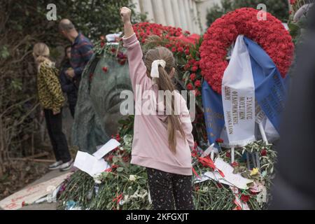 Athen, Griechenland. 17.. November 2022. Ein Mädchen hebt ihre linke Faust vor den riesigen Bronzekopf, der von der griechischen Skulptur Agamemnon Markis als Denkmal für alle, die während der Kundgebung während des Aufstands starben, geschaffen wurde. Feierlichkeiten an der Polytechnischen Schule von Athen und Kundgebung zum 49.. Jahrestag des Aufstands der Polytechnischen Studenten 1973 gegen die Militärjunta, die in Griechenland regierte. Kredit: SOPA Images Limited/Alamy Live Nachrichten Stockfoto