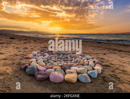 Während des Sonnenuntergangs am Strand werden rituelle Steine für spirituelle Zeremonien in Einem Kreis angeordnet Stockfoto