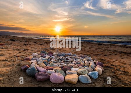 Während des Sonnenuntergangs am Strand werden rituelle Steine für spirituelle Zeremonien in Einem Kreis angeordnet Stockfoto