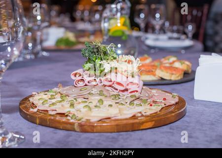 Schinken- und Käserollen auf einem Teller. Köstliche Vorspeise, Fleischkarbonat und Frischkäse. Vorspeise mit verschiedenen Wurstsorten auf der Platte serviert zu Wein Stockfoto