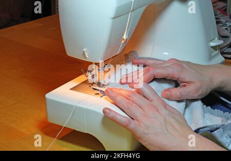 Nahaufnahme der Hände, die eine Nähmaschine bedienen. Stockfoto