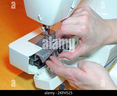 Nahaufnahme der Hände, die eine Nähmaschine bedienen. Stockfoto