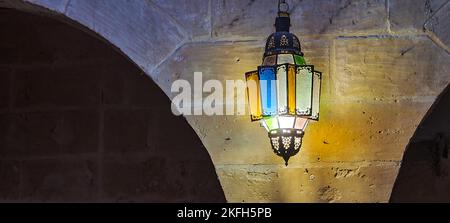 Eine alte Laterne mit Glasmalereien, die an der Wand hängen Stockfoto