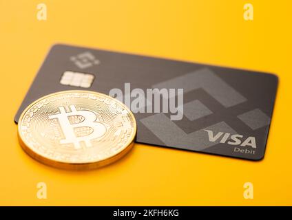 LONDON, Großbritannien - 19. NOVEMBER 2022: Binance Visa-Kreditkarte mit Bitcoin auf gelbem Hintergrund. Kryptowährungsplattform für Handel und Austausch. Draufsicht Stockfoto