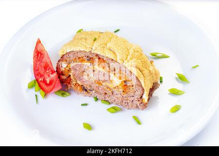 Eierrolle mit Fleisch, Käse und eingepickten Gurken in einer Platte, die mit Tomaten auf dem Tisch serviert wird. Horizontal Stockfoto