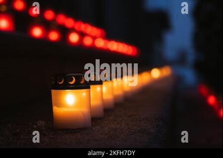 Rot-weiße brennende Kerzen auf Stufen, die die lettische Flagge symbolisieren. Der 18.. November ist die Feier des Unabhängigkeitstages in Lettland. Nahaufnahme. Stockfoto