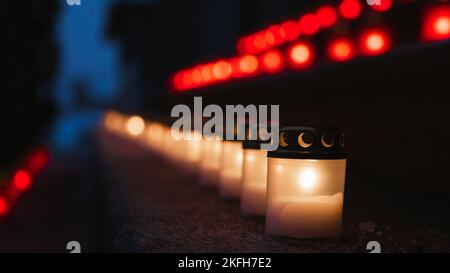 Rot-weiße brennende Kerzen auf Stufen, die die lettische Flagge symbolisieren. Der 18.. November ist die Feier des Unabhängigkeitstages in Lettland. Nahaufnahme. Stockfoto