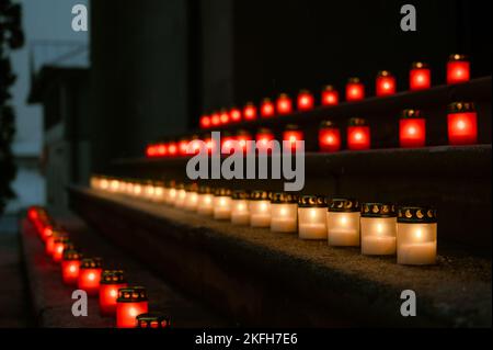 Rot-weiße brennende Kerzen auf Stufen, die die lettische Flagge symbolisieren. Der 18.. November ist die Feier des Unabhängigkeitstages in Lettland. Nahaufnahme. Stockfoto