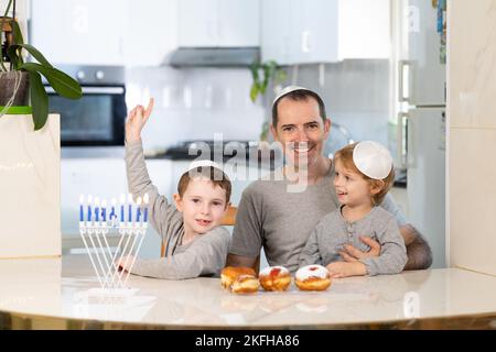 Vater und Söhne mit Menora feiern chanukka - jüdischer religiöser Feiertag Stockfoto