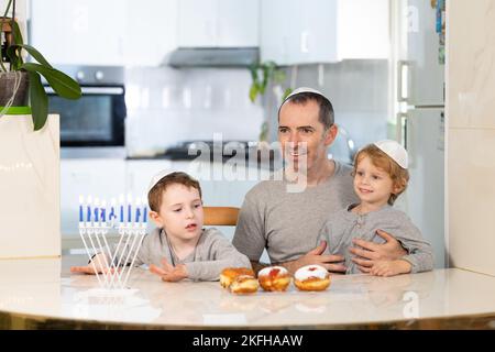 Vater und Söhne mit Menora feiern chanukka - jüdischer religiöser Feiertag Stockfoto