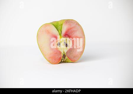 Eine Hälfte eines einzelnen lucy glo Apfels auf weißem Hintergrund Stockfoto