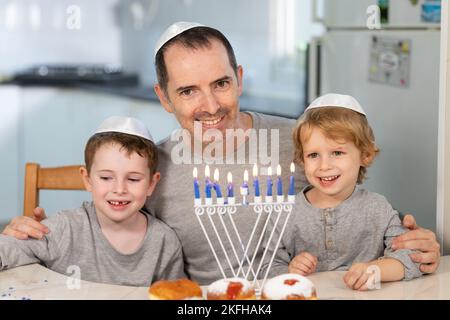 Vater und Söhne mit Menora feiern chanukka - jüdischer religiöser Feiertag Stockfoto