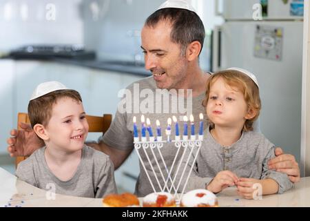 Vater und Söhne mit Menora feiern chanukka - jüdischer religiöser Feiertag Stockfoto