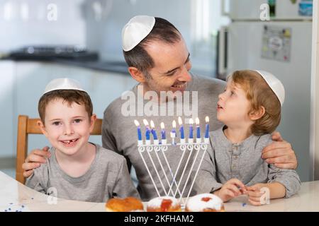 Vater und Söhne mit Menora feiern chanukka - jüdischer religiöser Feiertag Stockfoto