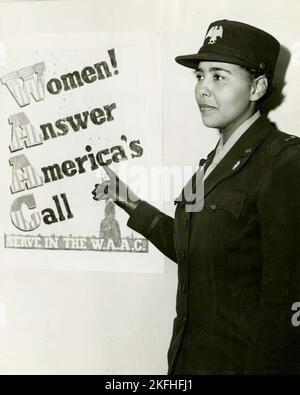 African American Charity Adams, First Officer im Hilfskorps der Frauenarmee, stand in Uniform und zeigte auf ein Plakat mit der Aufschrift: "Frauen! Beantwortet Amerikas Ruf, dient in der W.A.C.“, 1943-02. Stockfoto