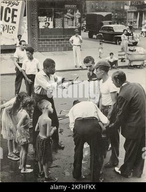 Eastside - eine Gruppe von Männern und Jugendlichen, die sich um ein Unfallopfer versammelten; ein junger Mann scheint mit den anderen zu streiten, East Harlem, New York City, 1947 - 1951. Stockfoto