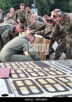 Reserve-Bürger-Airmen, die der 68. Airlift Squadron und Marines mit dem Marine Light Attack Helicopter Squadron zugewiesen wurden – 773, Det. Alpha Bewegen Sie Holzbretter an ihren Platz, um beim Laden von zwei Marine-Hubschraubern auf ein C-5M Super Galaxy Flugzeug zu helfen 13. September 2022, auf der Naval Air Station Joint Reserve Base New Orleans, Louisiana. Die Flugzeuge und Hubschrauber wurden während der NATO Days 22. in Ostrava, Tschechien, vom 17. Bis 18. September 2022 ausgestellt. Stockfoto