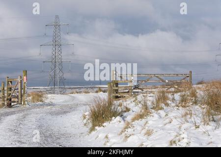 Breites Fahrzeugtor aus Holz und separates Fußwegtor an den Rossendale Moors. Schneebedeckte Wege und Moore Stockfoto