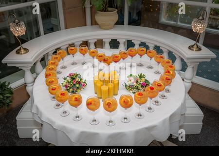 Herzförmige Cocktailgetränke auf dem Tisch mit weißem Tuch. Zwei Brautsträuße während des Hochzeitsempfangs am Hochzeitstag. Stockfoto