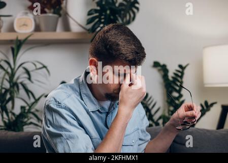Nahaufnahme des müden jungen männlichen Computerbenutzers nimmt die Brille ab massiert trocken juckende, reizende Augen fühlen sich Augenbelastung an. Überarbeitter Telearbeiter löst t Stockfoto