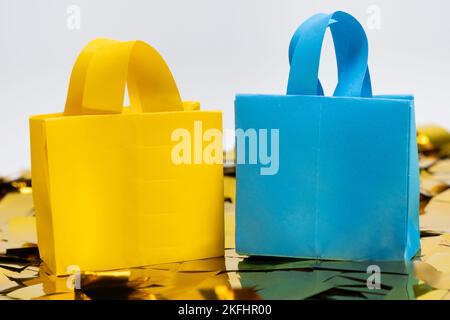 Gelbe und blaue Origami-Taschen aus Papier auf Funkeln. Das Konzept der Käufe und Verkäufe Stockfoto