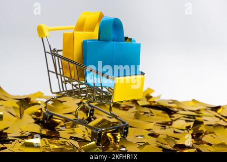 Einkaufstaschen im Karren auf Pailletten auf weißem Hintergrund. Das Konzept des Verkaufs. Stockfoto