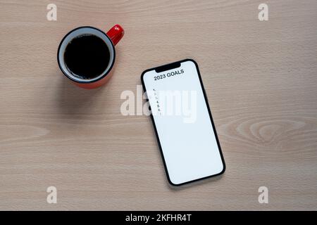 Mobiltelefon mit 2023 Zielen Text, um Neujahrsvorsätze umzusetzen und am Schreibtisch mit einem Café zu planen Stockfoto