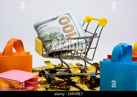 Einkaufstaschen und ein Wagen mit Geld auf weißem Hintergrund. Das Konzept des Verkaufs. Stockfoto