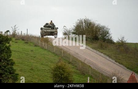 Britische Armee Warrior FV510 Kampffahrzeug in Aktion Fahren auf einer Schlammspur bei einer militärischen Kampfübung, Wiltshire UK Stockfoto