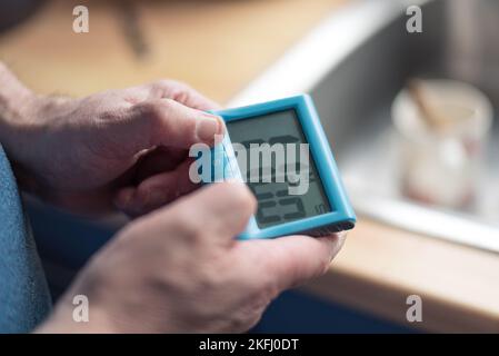 Mann stellt einen blauen Timer ein. 11 Minuten auf der Uhr zum Backen. Beide Hände. Stockfoto