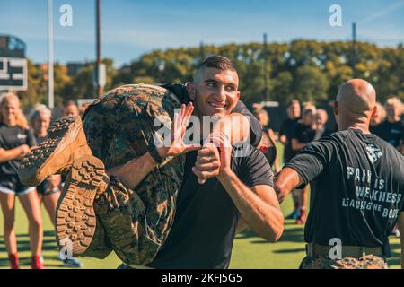 Midshipman William Attisha mit dem Naval Reserve Officers Training Corps - Massachusetts Institute of Technology, demonstriert eine ordnungsgemäße Feuerwehrmann tragen für das Feldhockey-Team der Harvard University bei einem Team-und Führungsseminar von den Marines mit Officer Selection Station Boston in Cambridge, Massachusetts, 17. September 2022 statt. Das Hockeyteam nahm am Kampffitnesstest des Marine Corps Teil, der aus einem 880-Meter-Lauf, Munitionsliften und einem Manöver unter Feuerübung besteht. Auf jede Veranstaltung folgten Teamarbeit und Führungsgespräche. Stockfoto