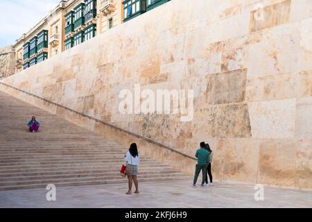 Valletta, Malta - 12. November 2022: Riesige Steinmauer und Treppen im Rahmen des Renzo Piano-Wiederaufbauprojekts und traditioneller Valletta-Holzbalkon Stockfoto