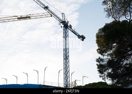 Auf einer Baustelle arbeiten Krane, die den Transport von Baumaterialien unterstützen, einschließlich Stockfoto