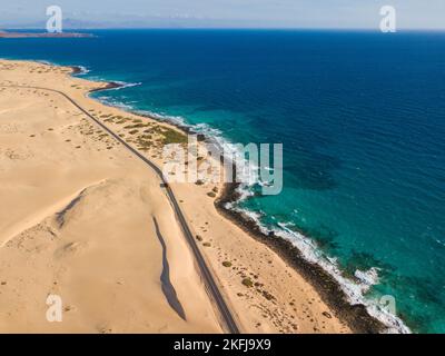 Felsige Küste und Autobahn mit goldenem Sand und blauem Wasser Stockfoto