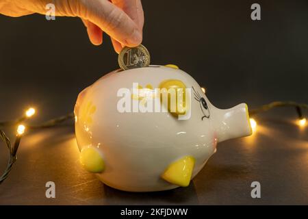 Eine Euro-Münze in einem Sparschwein auf dunklem Hintergrund mit kleinen LED-Lichtern. Konzept der Kostenersparnis. Speicherplatz kopieren. Stockfoto