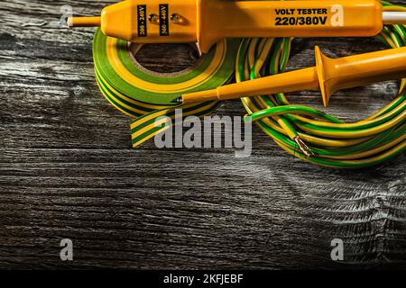 Elektrotester sucht nach gewalztem Kabelisolierband auf Holzbrett. Stockfoto