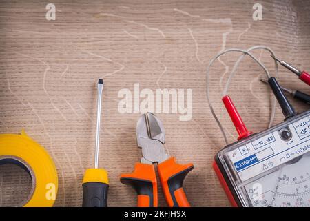 Der alte elektrische Tester zwickt das Isolierband des Schraubendrehers. Stockfoto