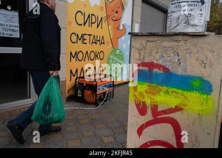 Cherson, Ukraine. 17.. November 2022. Ein Mann, der humanitäre Hilfe trägt, kommt an einem Laden vorbei, in dem sich ein Generator im Freien befinden. Die Bewohner von Kherson sind immer noch überglücklich über die Befreiung der Stadt und setzen mehr als 8 Monate der Besetzung zu Ende. Dennoch verfügt die südliche regionale Hauptstadt noch immer über keinen Strom, kein Wasser und ein Minimum an Signal- und Nahrungsmittelversorgung. Kredit: SOPA Images Limited/Alamy Live Nachrichten Stockfoto