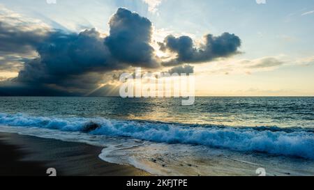 Ein Sonnenuntergang Im Ozean Mit Sonnenstrahlen, Die Hinter Den Wolken Im 16,9-Bildformat Ausstrahlen Stockfoto