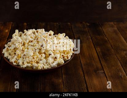 Eine Schüssel mit köstlichem Popcorn auf einem Holztisch, natürliches leckeres Essen zum Ansehen eines Films Stockfoto